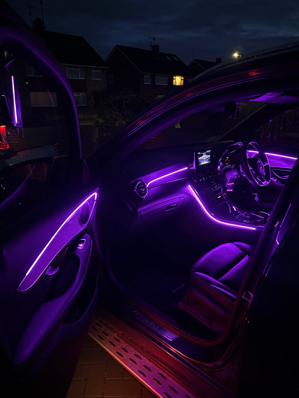 Car interior with purple LED lights on a dark night.